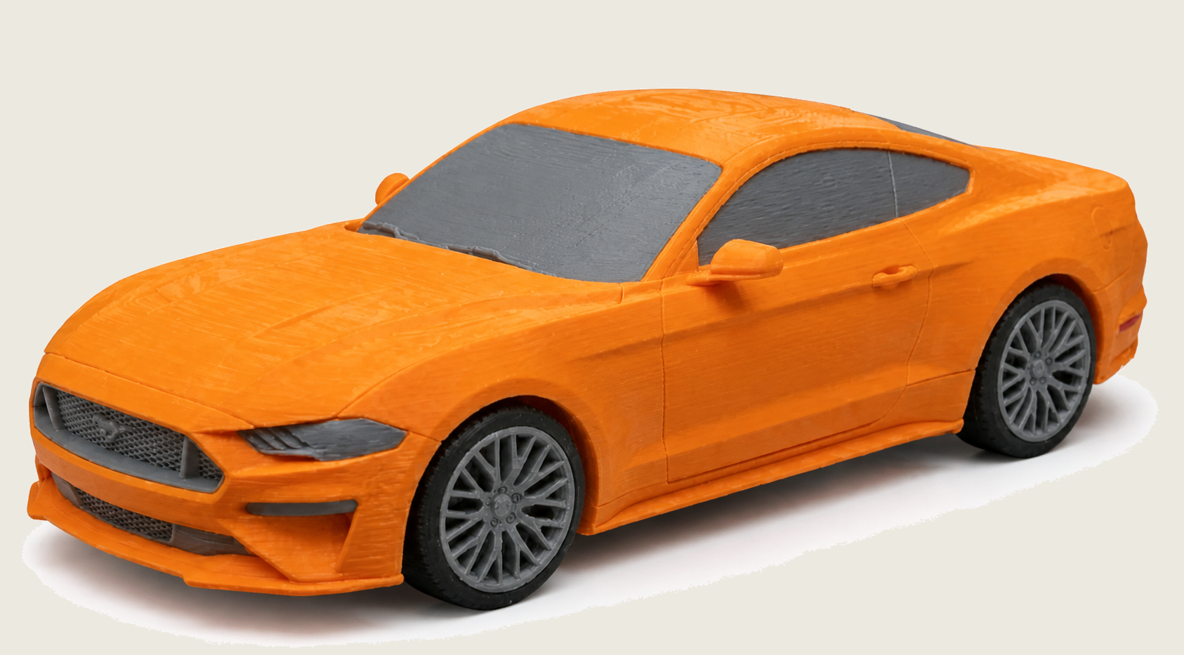 Orange 3D printed Mustang model on a darker soft off-white studio background