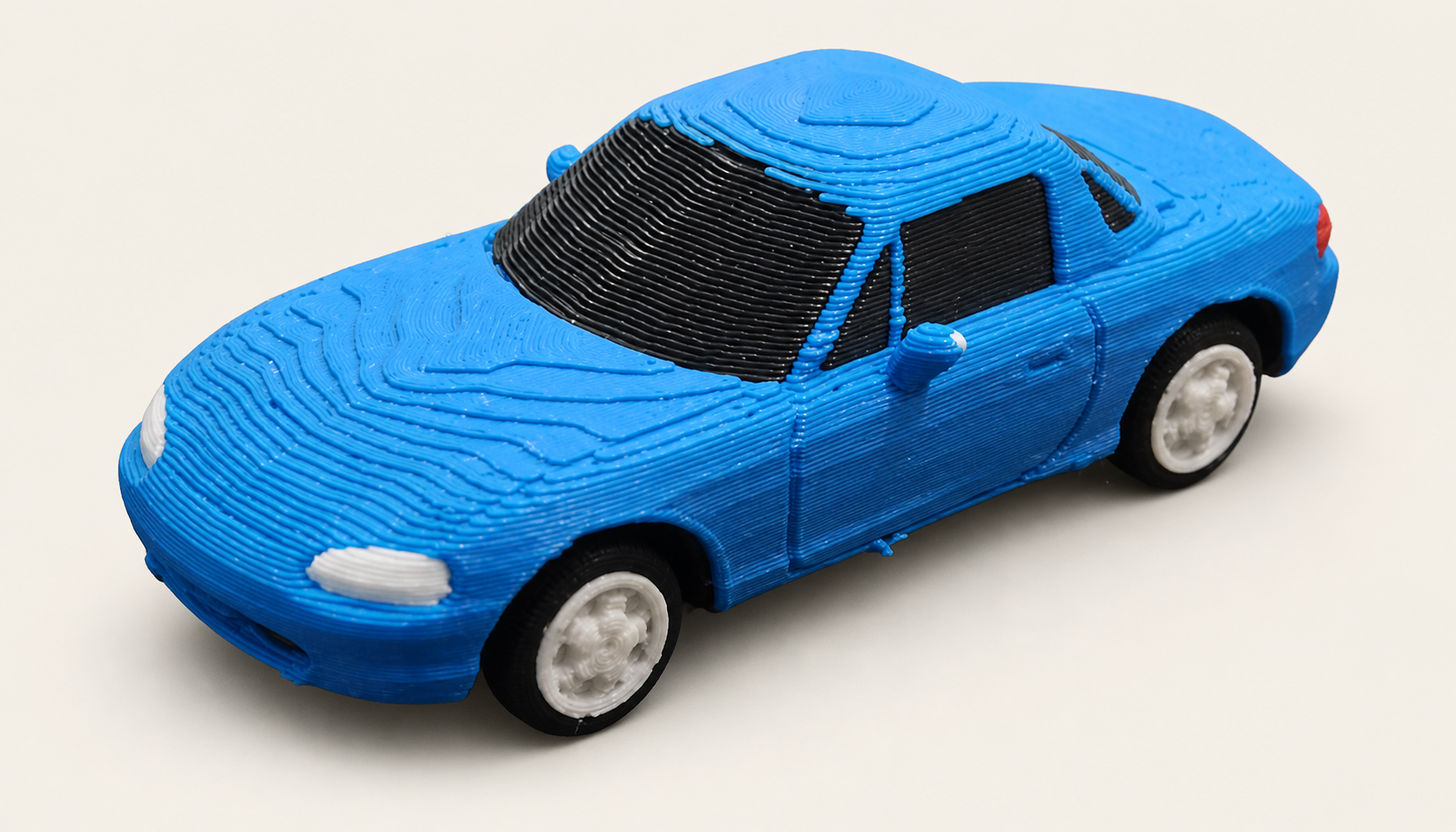 Blue Mazda Miata 3D-printed model on a soft off-white studio background
